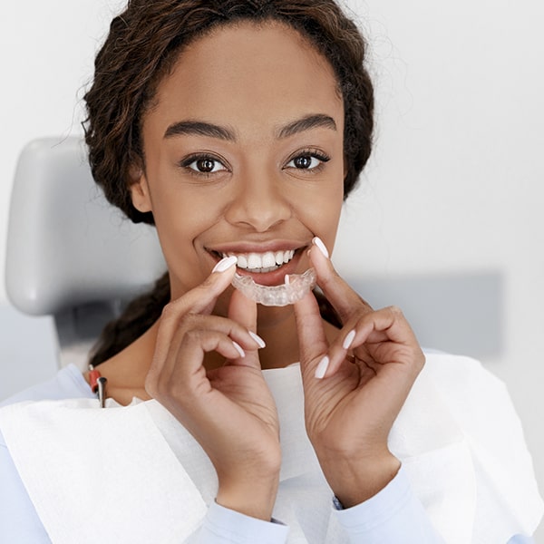 A female patient holding a set of clear aligners
