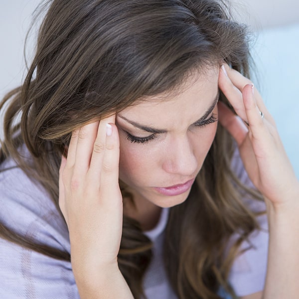 A woman having a migraine due to her TMJ problem