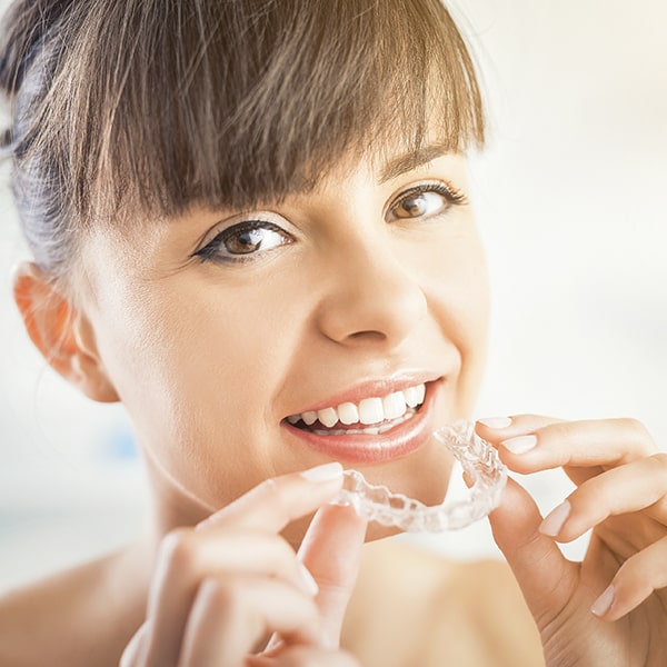 A woman putting on Invisalign® aligners